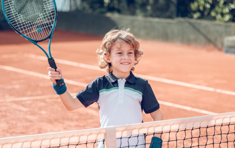 positive-kid-raising-racket-while-playing-tennis-o-2023-11-27-05-02-10-utc 1